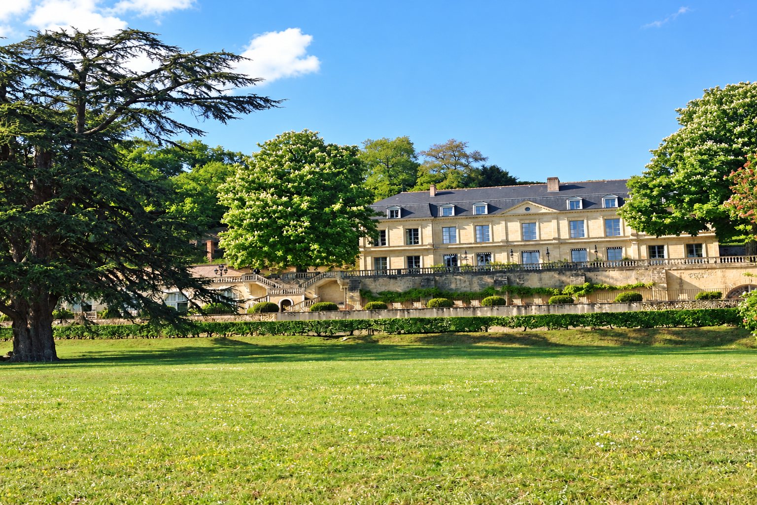 Château en pierre claire dans un parc arboré