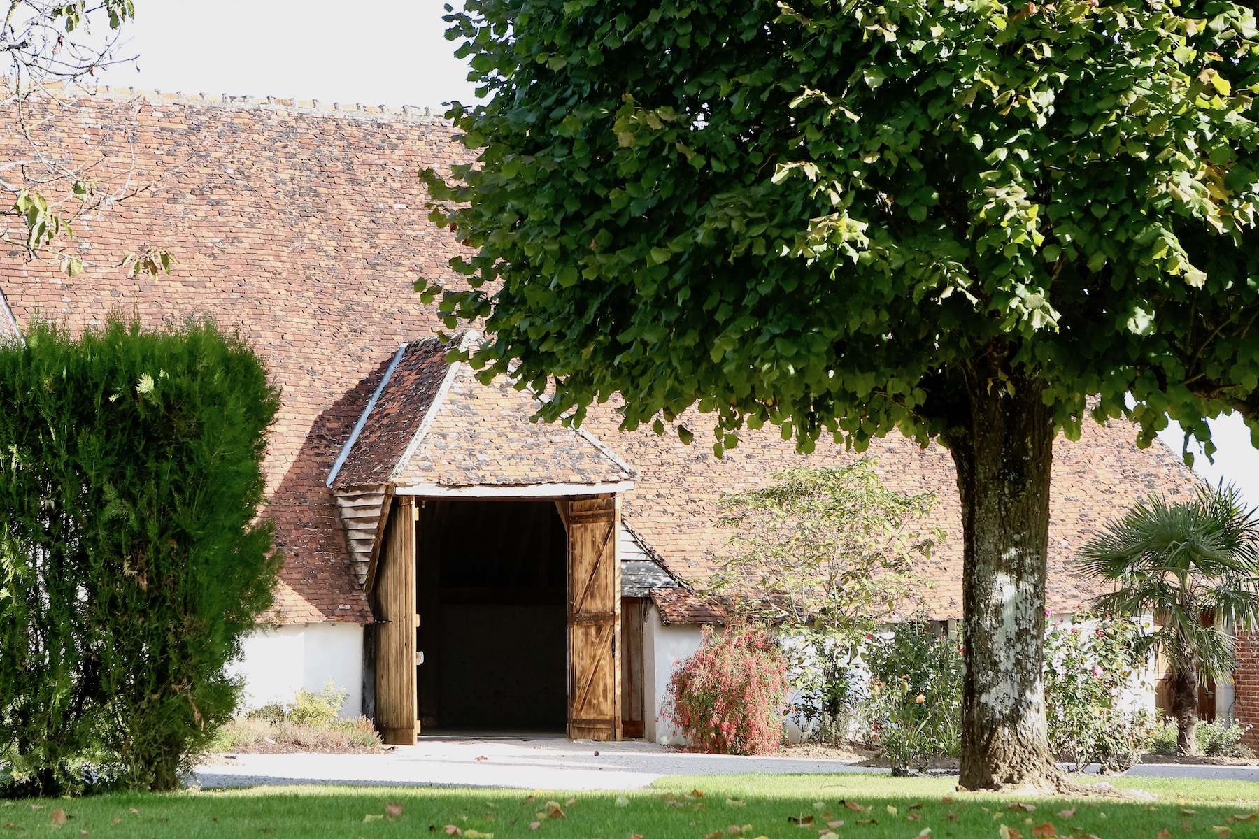 Ancienne grange au toit de tuiles, porte en bois ouverte